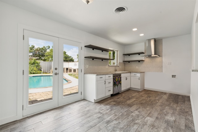 kitchen with dishwasher, french doors, wall chimney range hood, tasteful backsplash, and white cabinets