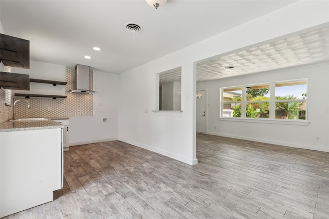 kitchen featuring decorative backsplash, sink, wall chimney exhaust hood, and light wood-type flooring