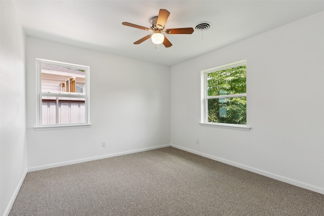 carpeted spare room featuring ceiling fan and a healthy amount of sunlight