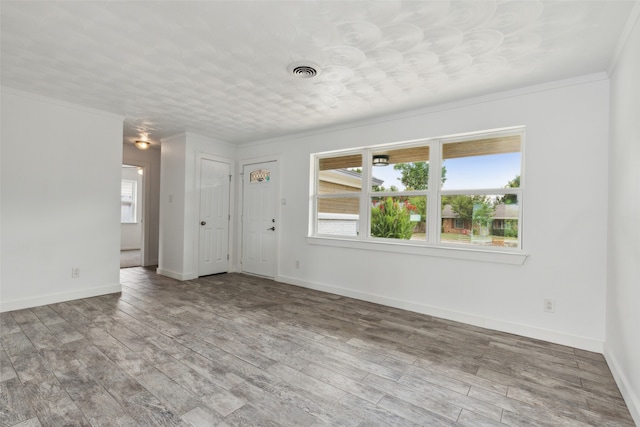 empty room featuring hardwood / wood-style floors, plenty of natural light, and ornamental molding