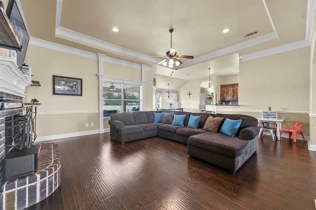 living room featuring ornamental molding, wood-type flooring, ceiling fan, and a raised ceiling