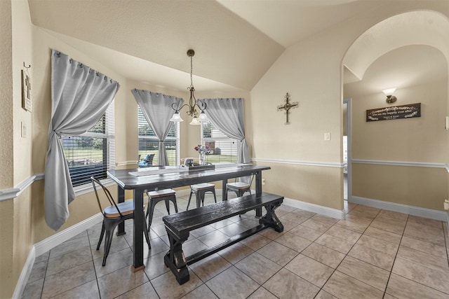 tiled dining room featuring an inviting chandelier and lofted ceiling