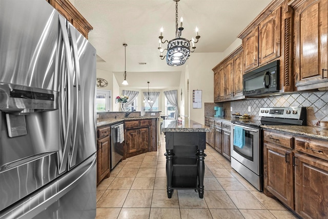 kitchen with dark stone counters, hanging light fixtures, decorative backsplash, light tile patterned floors, and stainless steel appliances