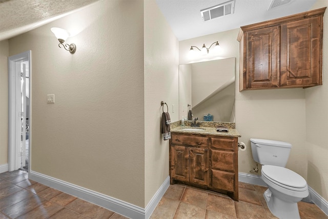 bathroom with tile patterned floors, toilet, vanity, and a textured ceiling