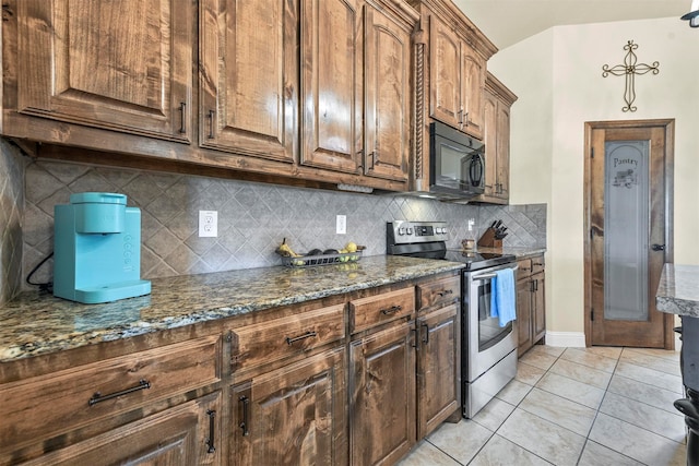 kitchen with light tile patterned flooring, backsplash, stainless steel electric range, and dark stone counters