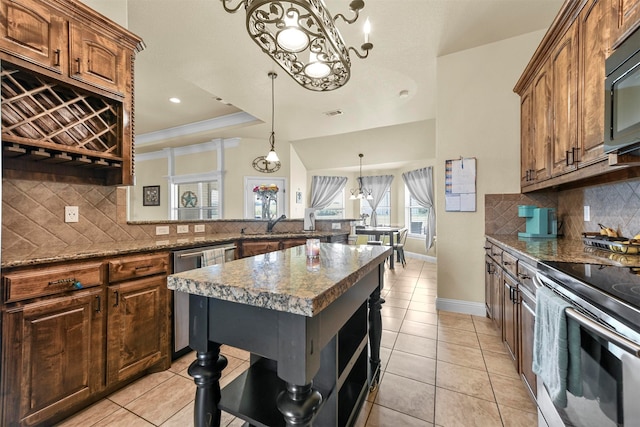 kitchen with an inviting chandelier, a center island, hanging light fixtures, appliances with stainless steel finishes, and decorative backsplash