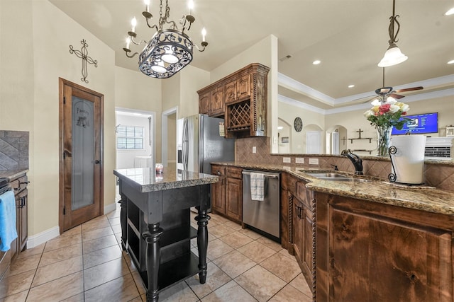 kitchen featuring appliances with stainless steel finishes, tasteful backsplash, sink, a kitchen island, and ceiling fan with notable chandelier