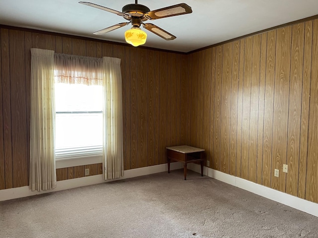 spare room with carpet floors, ceiling fan, and wood walls