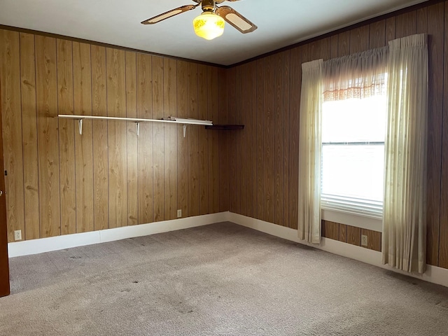 empty room featuring wooden walls, ceiling fan, and carpet flooring