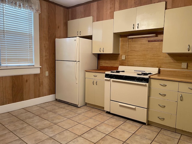 kitchen featuring wooden walls, light tile patterned floors, and white appliances