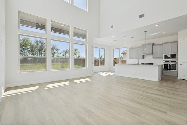 unfurnished living room with light wood-type flooring, visible vents, baseboards, and recessed lighting