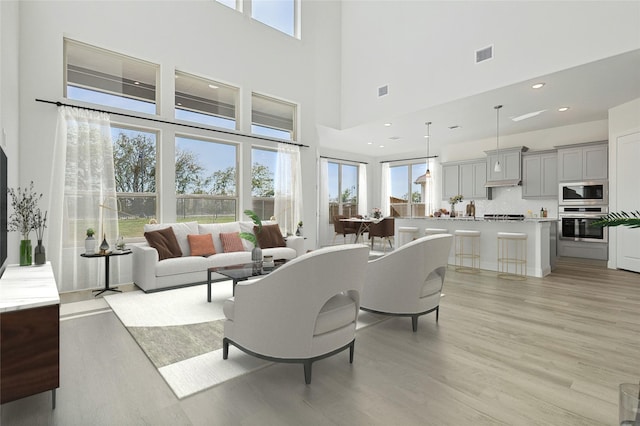 living room featuring light wood-type flooring, plenty of natural light, visible vents, and recessed lighting