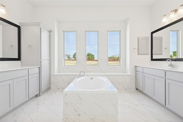 bathroom with vanity, tiled bath, and a healthy amount of sunlight