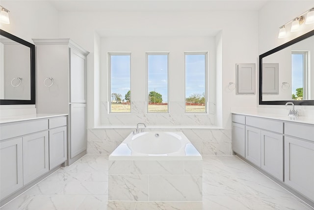 bathroom with marble finish floor, vanity, and a tub