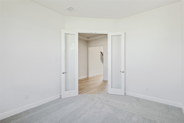 unfurnished room with french doors and light colored carpet