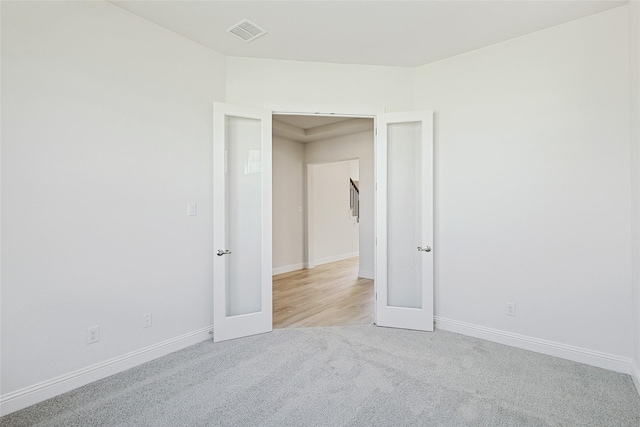 unfurnished room with baseboards, visible vents, and light colored carpet