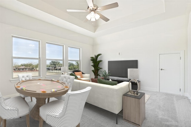 living area with carpet, baseboards, a raised ceiling, and a ceiling fan