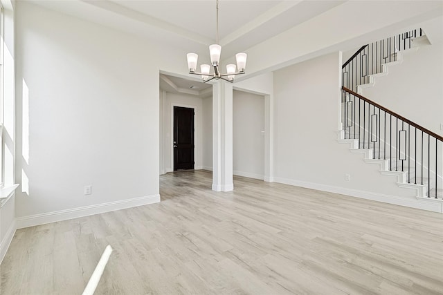 unfurnished dining area with stairs, a chandelier, light wood-style flooring, and baseboards