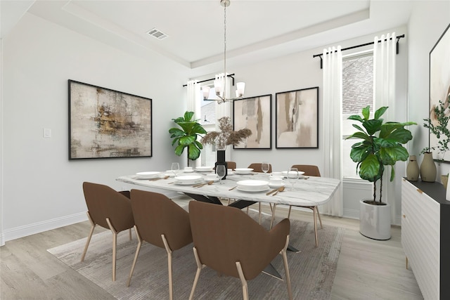 dining space featuring light wood-style flooring, a notable chandelier, visible vents, baseboards, and a tray ceiling