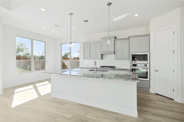 kitchen with appliances with stainless steel finishes, decorative light fixtures, light wood-type flooring, and gray cabinets