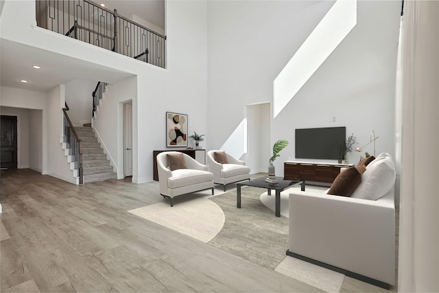 living room with stairs, a towering ceiling, light wood-style flooring, and baseboards