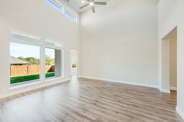 unfurnished living room featuring a high ceiling, light hardwood / wood-style floors, and a wealth of natural light