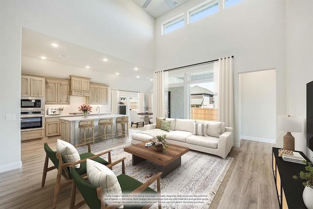 living room featuring light hardwood / wood-style flooring, a healthy amount of sunlight, a high ceiling, and sink