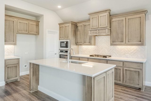 kitchen featuring vaulted ceiling, sink, an island with sink, and stainless steel appliances