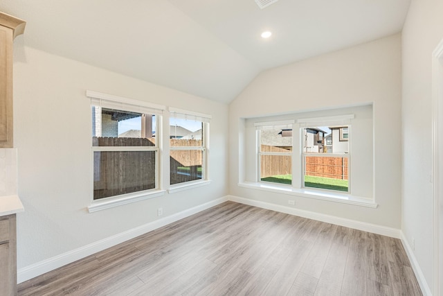 interior space featuring plenty of natural light, light wood-type flooring, and vaulted ceiling