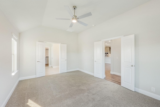 unfurnished bedroom with light colored carpet, vaulted ceiling, and ceiling fan