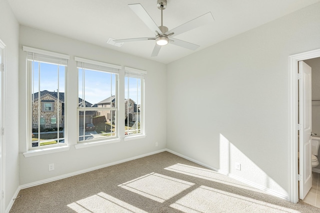 carpeted spare room featuring plenty of natural light and ceiling fan