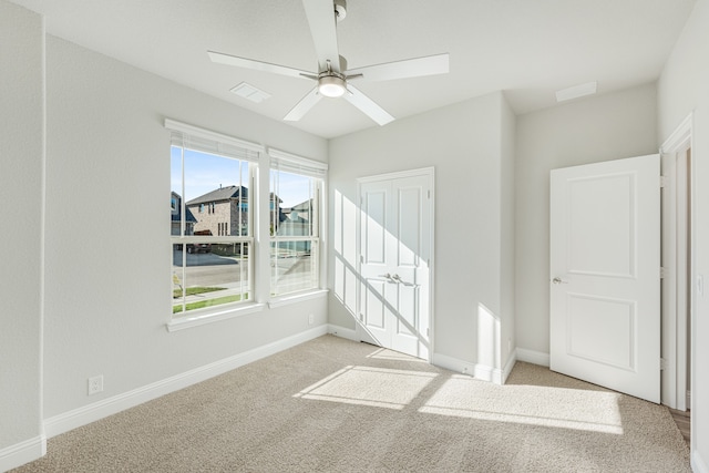 carpeted empty room with ceiling fan and a healthy amount of sunlight