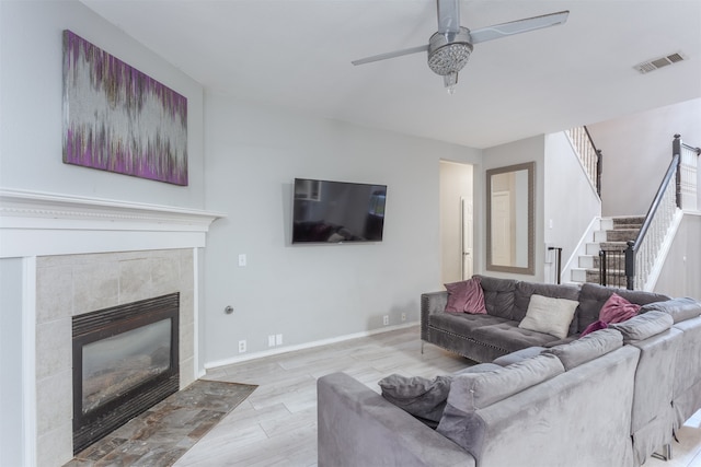 living room featuring light hardwood / wood-style flooring, a fireplace, and ceiling fan