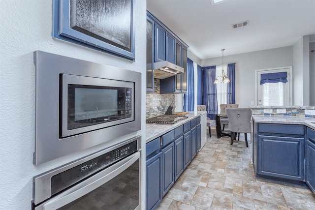 kitchen with an inviting chandelier, backsplash, blue cabinets, appliances with stainless steel finishes, and pendant lighting