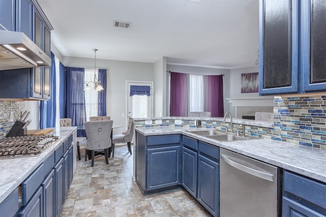 kitchen with a chandelier, stainless steel appliances, wall chimney exhaust hood, decorative backsplash, and sink