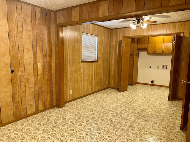 interior space featuring wood walls, a textured ceiling, and ceiling fan