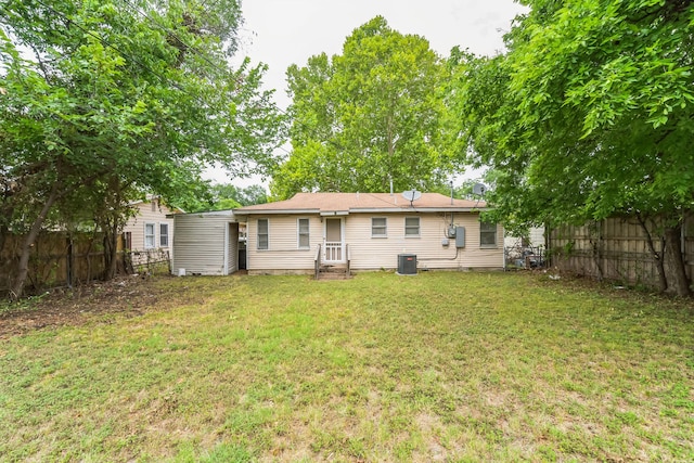 rear view of house with a yard and central AC