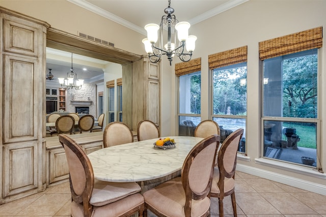 dining room featuring an inviting chandelier, a fireplace, crown molding, and light tile patterned floors