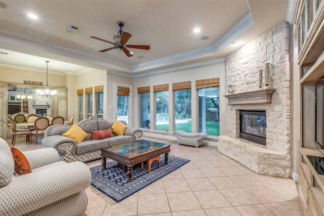 living room with ornamental molding, light tile patterned floors, a fireplace, and ceiling fan with notable chandelier