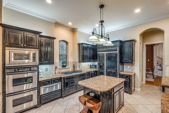 kitchen with built in appliances, hanging light fixtures, backsplash, and a kitchen island