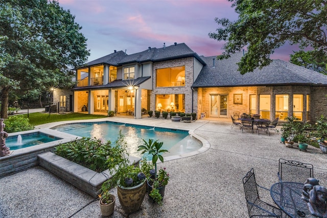 back house at dusk with a patio and a swimming pool with hot tub