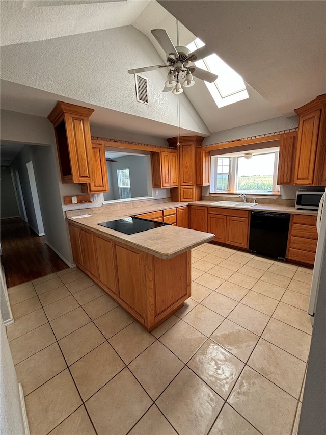 kitchen featuring black appliances, ceiling fan, kitchen peninsula, and lofted ceiling with skylight