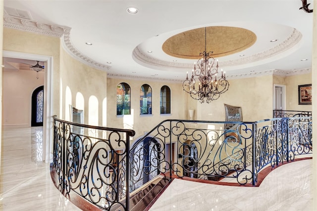 hallway with an inviting chandelier, crown molding, tile patterned flooring, and a tray ceiling