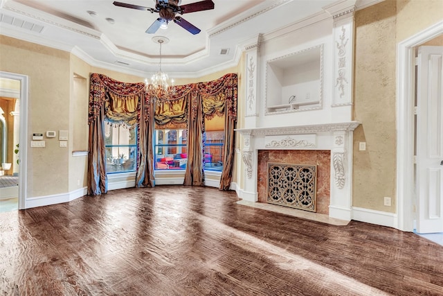 unfurnished living room featuring a fireplace, wood-type flooring, ceiling fan with notable chandelier, crown molding, and a raised ceiling