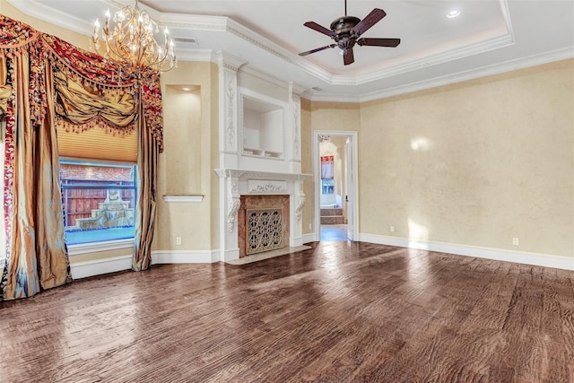 unfurnished living room with ceiling fan with notable chandelier, a raised ceiling, hardwood / wood-style floors, and ornamental molding