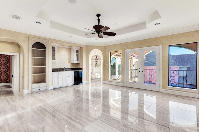 unfurnished living room with a raised ceiling, french doors, and light tile patterned floors