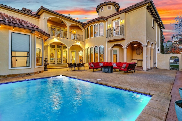 pool at dusk featuring a patio area and outdoor lounge area