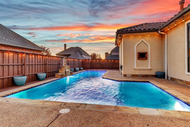 pool at dusk with a patio area