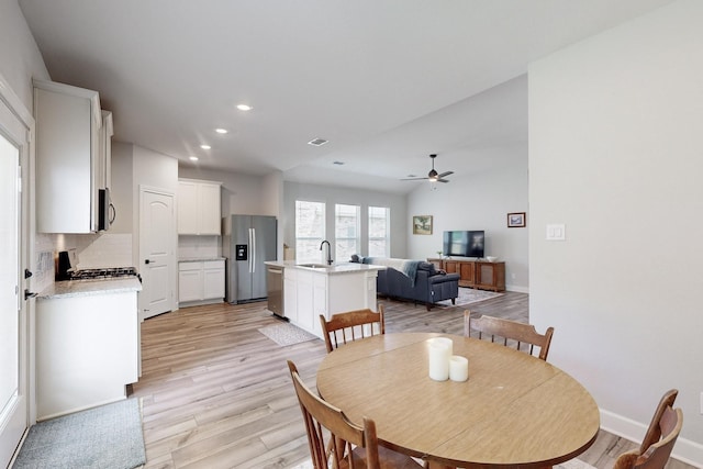 dining space with ceiling fan, light hardwood / wood-style floors, and sink