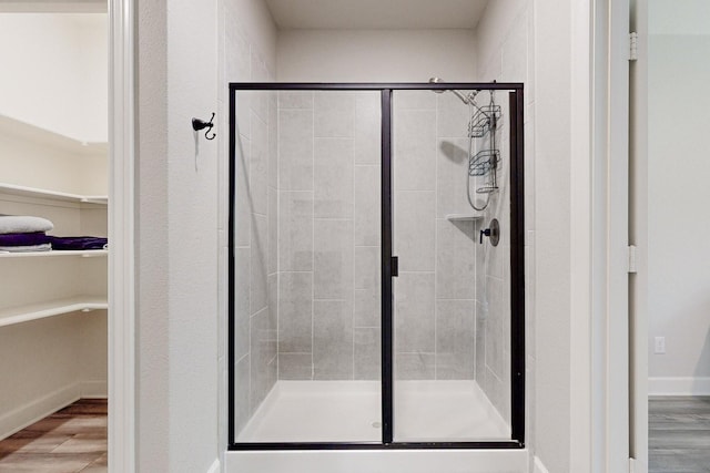 bathroom with a shower with door and wood-type flooring